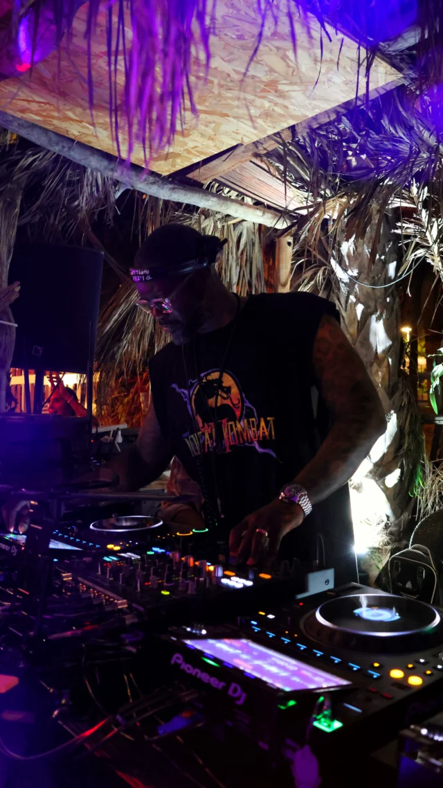 DJ aux platines sous une paillote en bord de mer, de nuit