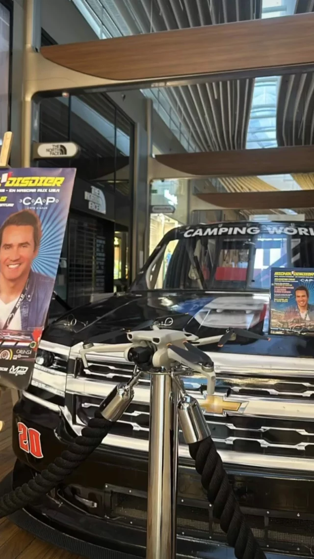 Stock-car NASCAR exposé en galerie commerciale, drone posé sur le capot