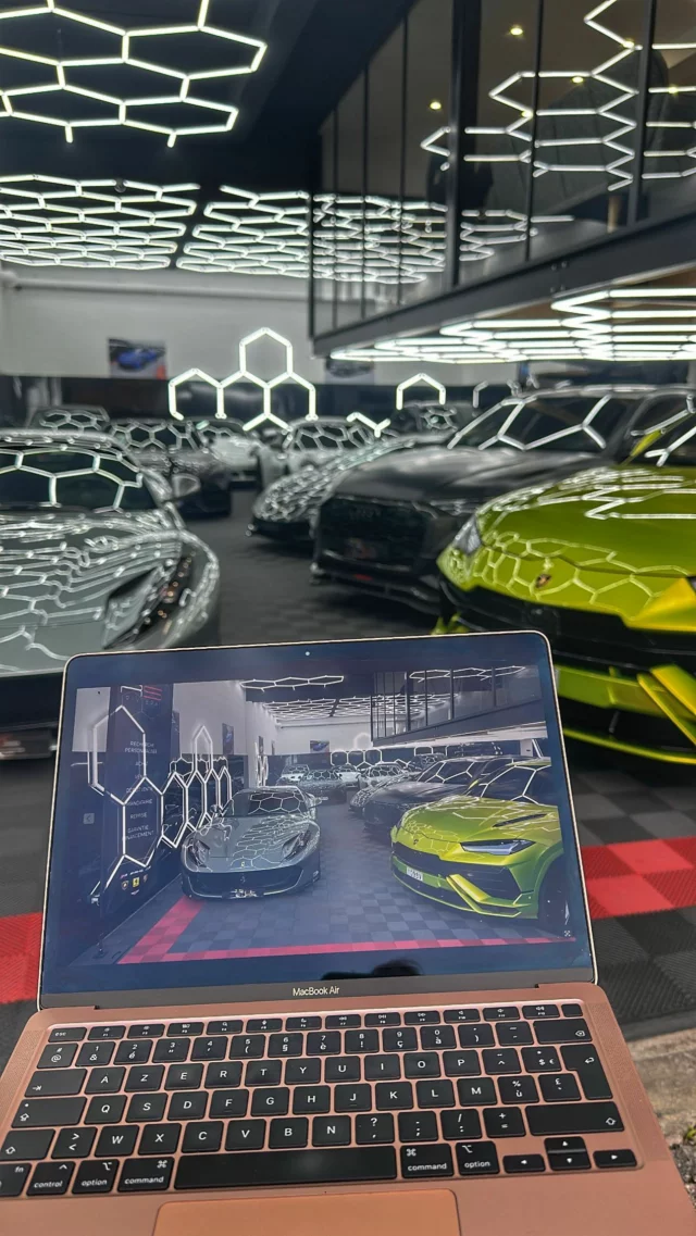 Montage vidéo sur ordinateur portable au milieu d'un showroom de voitures de sport